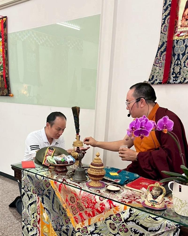 兩位參與者在鋪有彩色桌布的供桌前進行儀式。