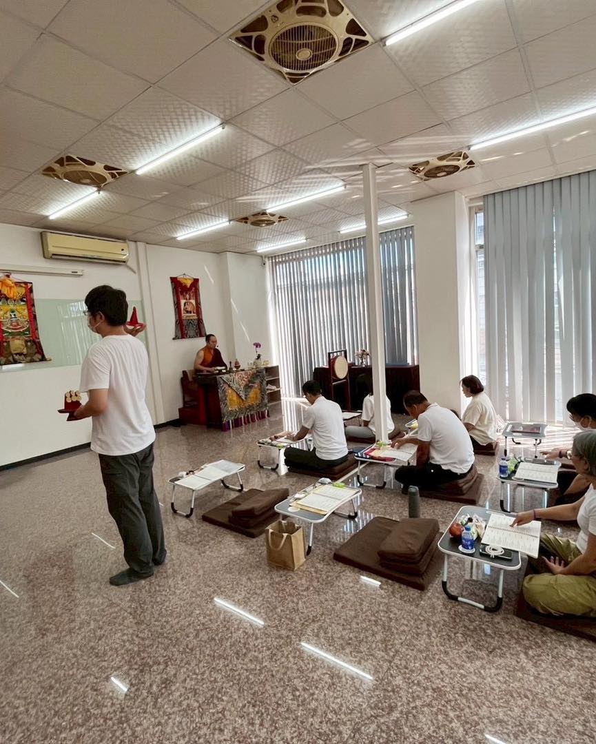 多位參與者在室內席地而坐聆聽站立者說話。