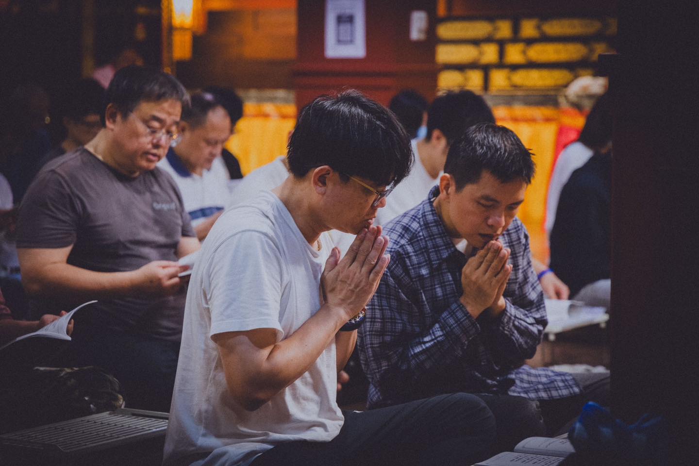 多位參與者坐在佛堂內雙手合十。