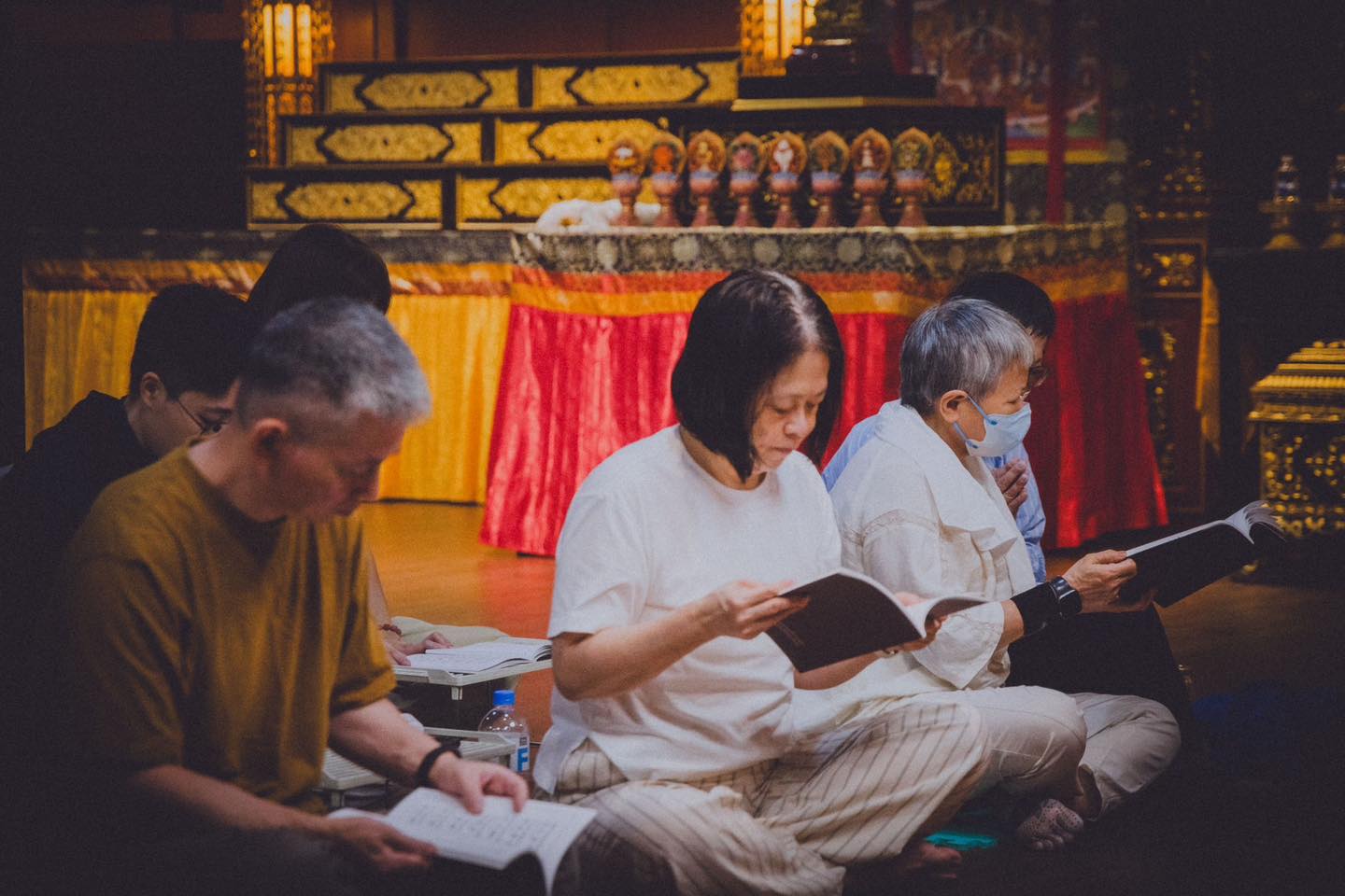 參與者坐在供壇旁閱讀經本。