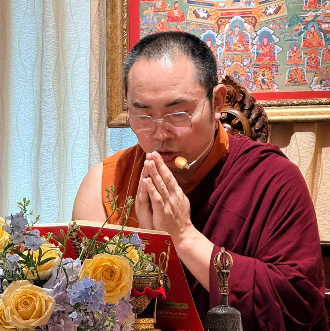 穿袈裟者在花束前雙手合十。