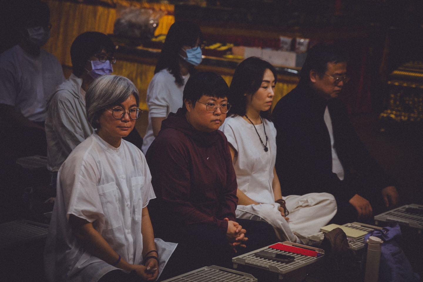 三位參與者席地而坐，前方可見供壇。