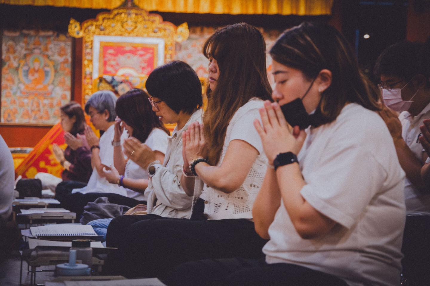 參與者在供壇前俯身閱讀桌上紙本。