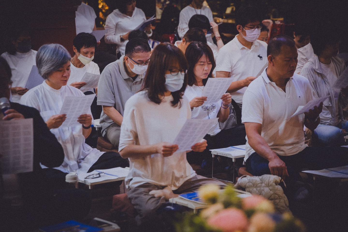 供壇前，多位參與者低頭閱讀或書寫。