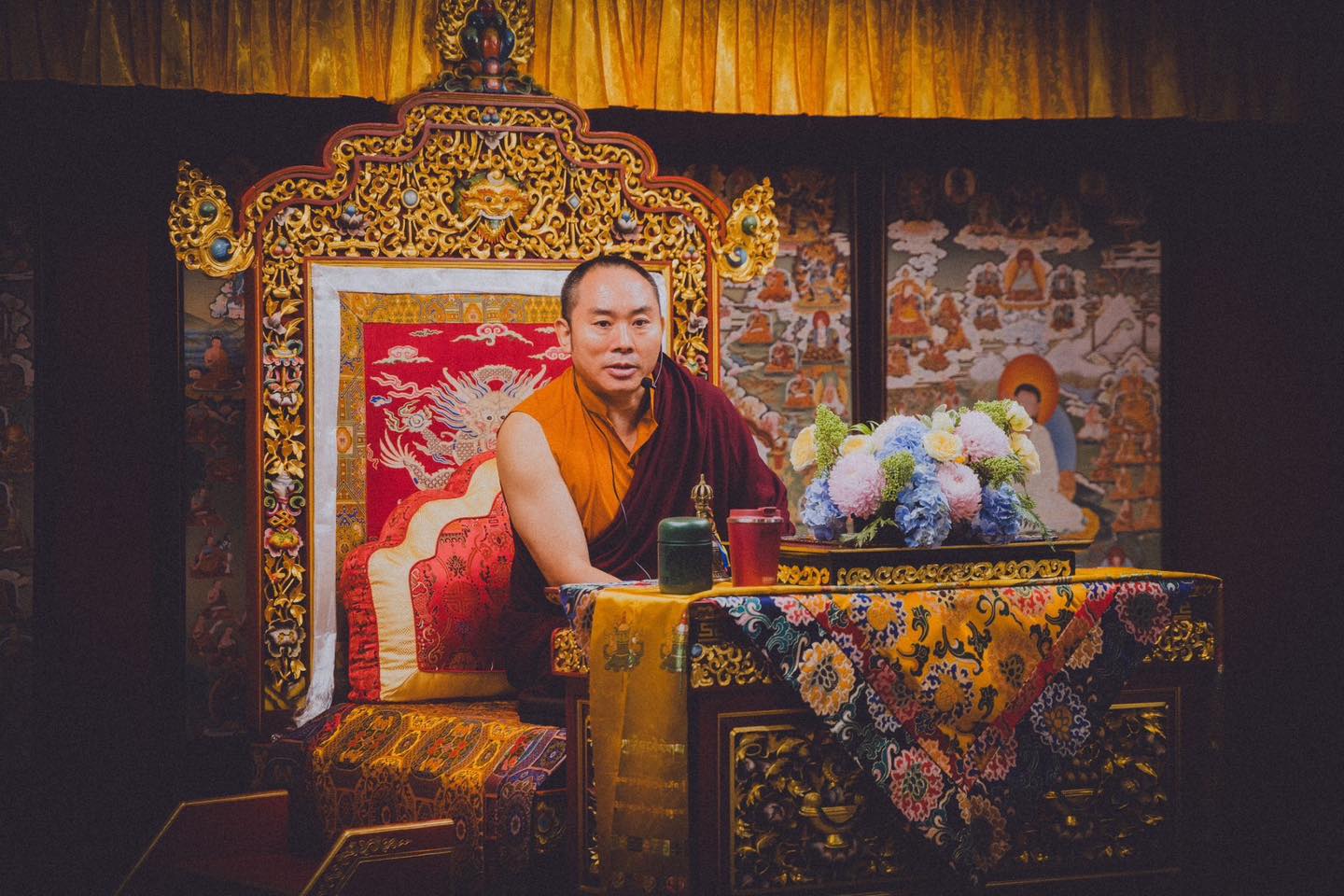 一位參與者坐在法座上，背景為佛堂壁畫。