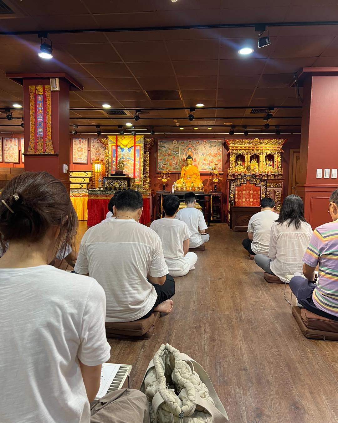 佛堂內，數位穿白衣的參與者面向供壇席地而坐。