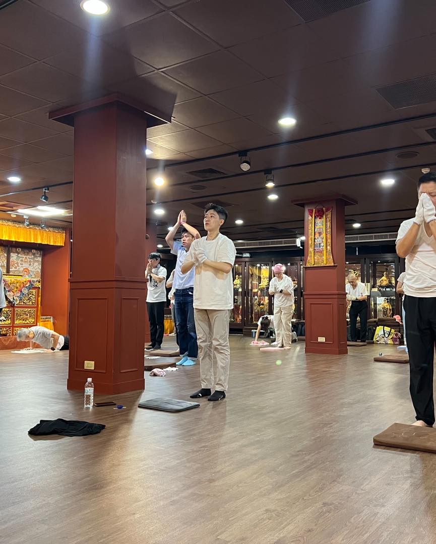 低角度拍攝,多位參與者在佛堂地板上禮拜。